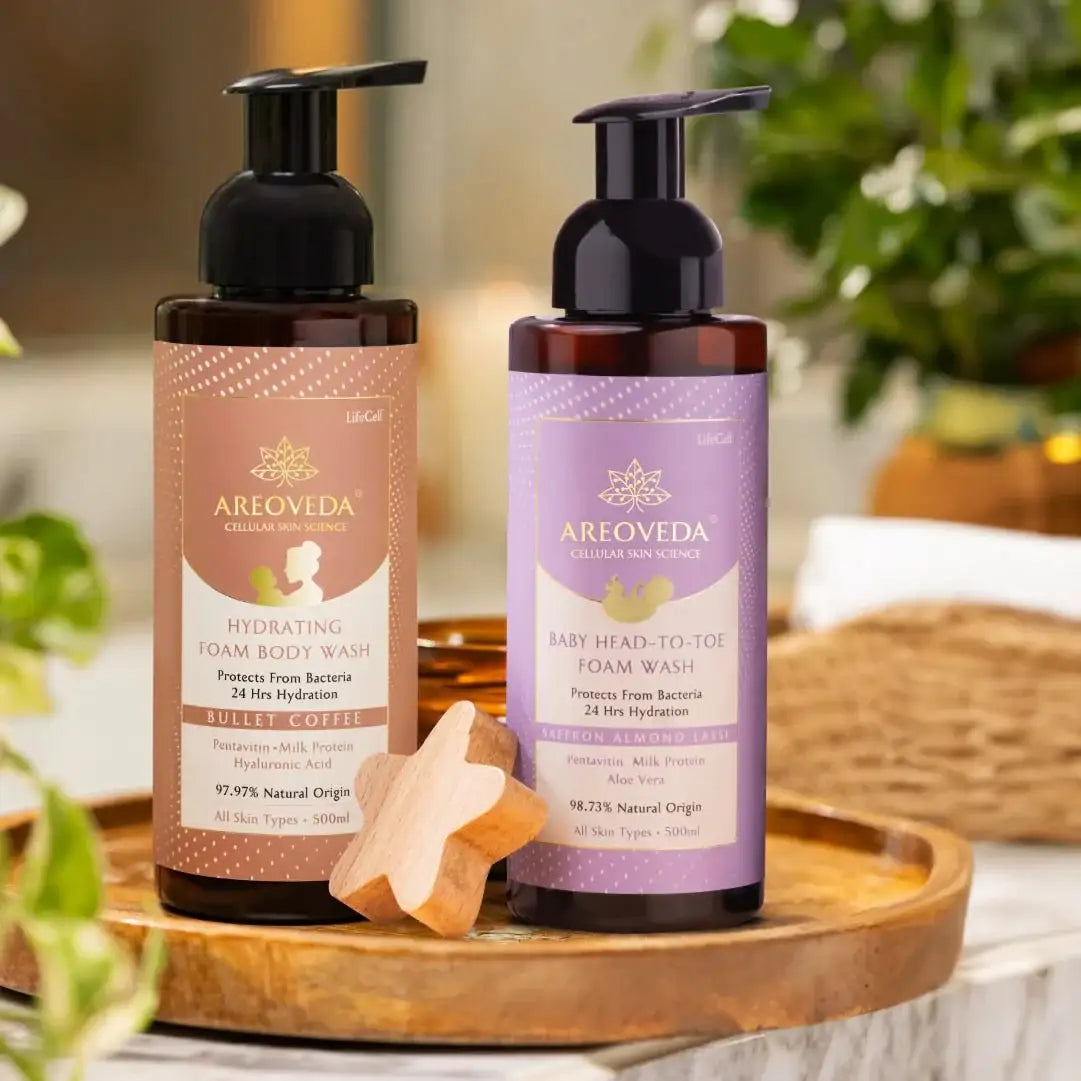 Two bottles of Areoveda foam body wash on a wooden tray with a blurred natural background